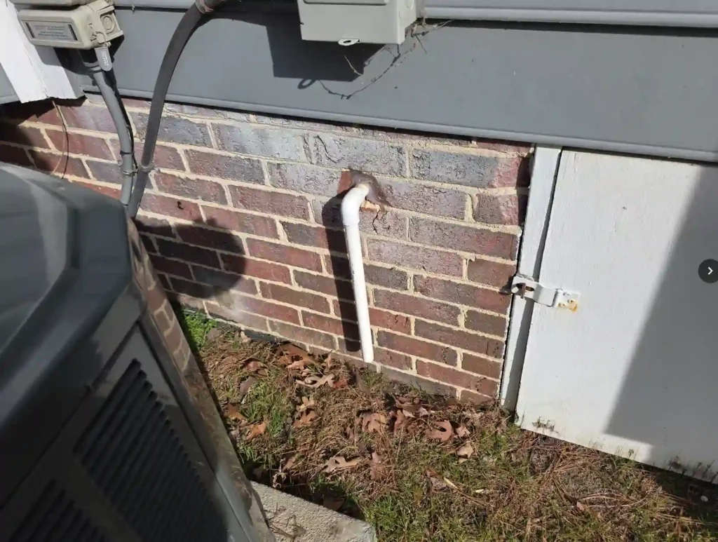 An AC condensation line dripping 12 gallons of water daily next to a foundation wall, causing saturated soil and increasing the risk of footer settling and crawl space moisture